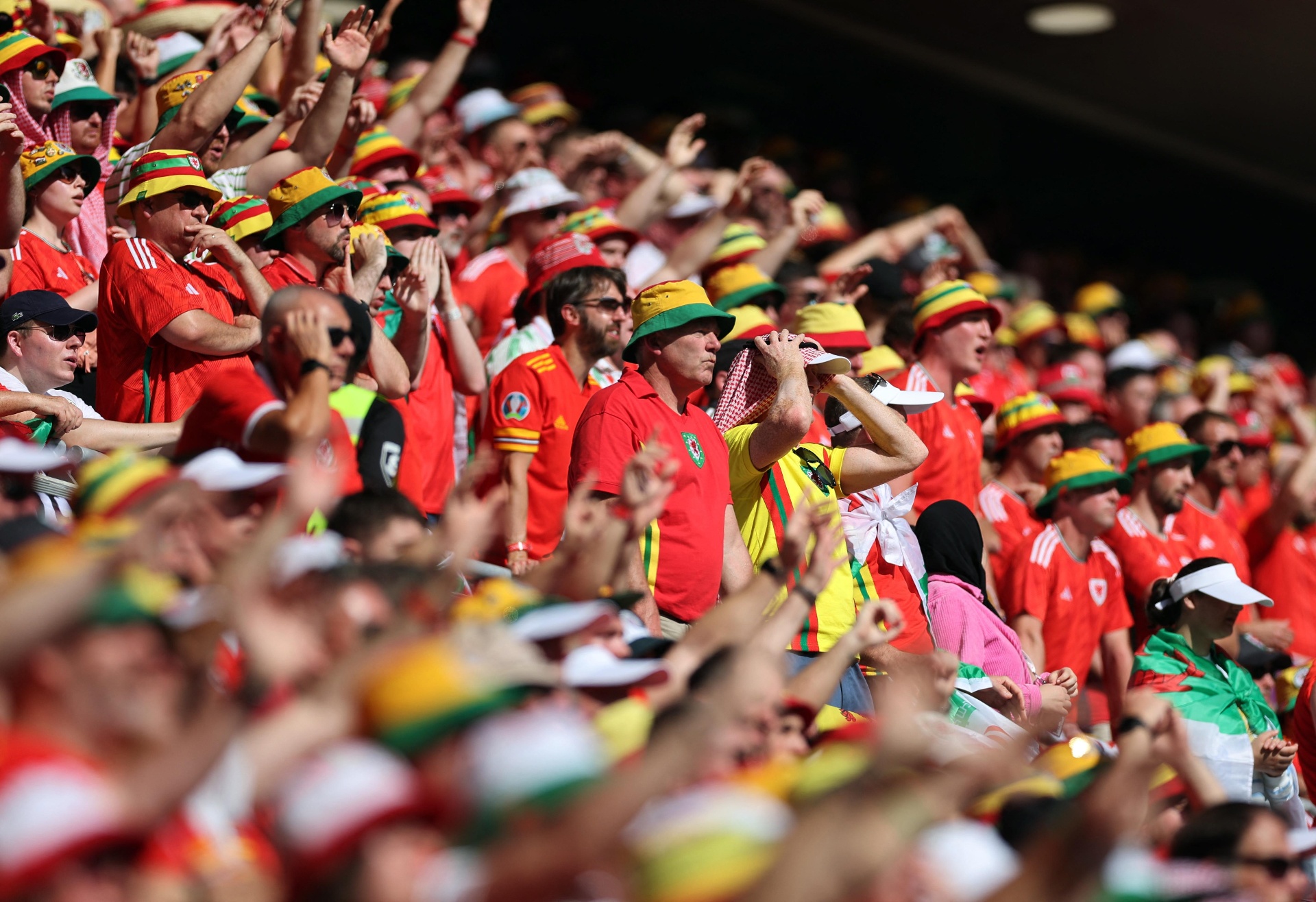 A sea of Welsh supporters in red shirts and yellow-and-green bucket hats